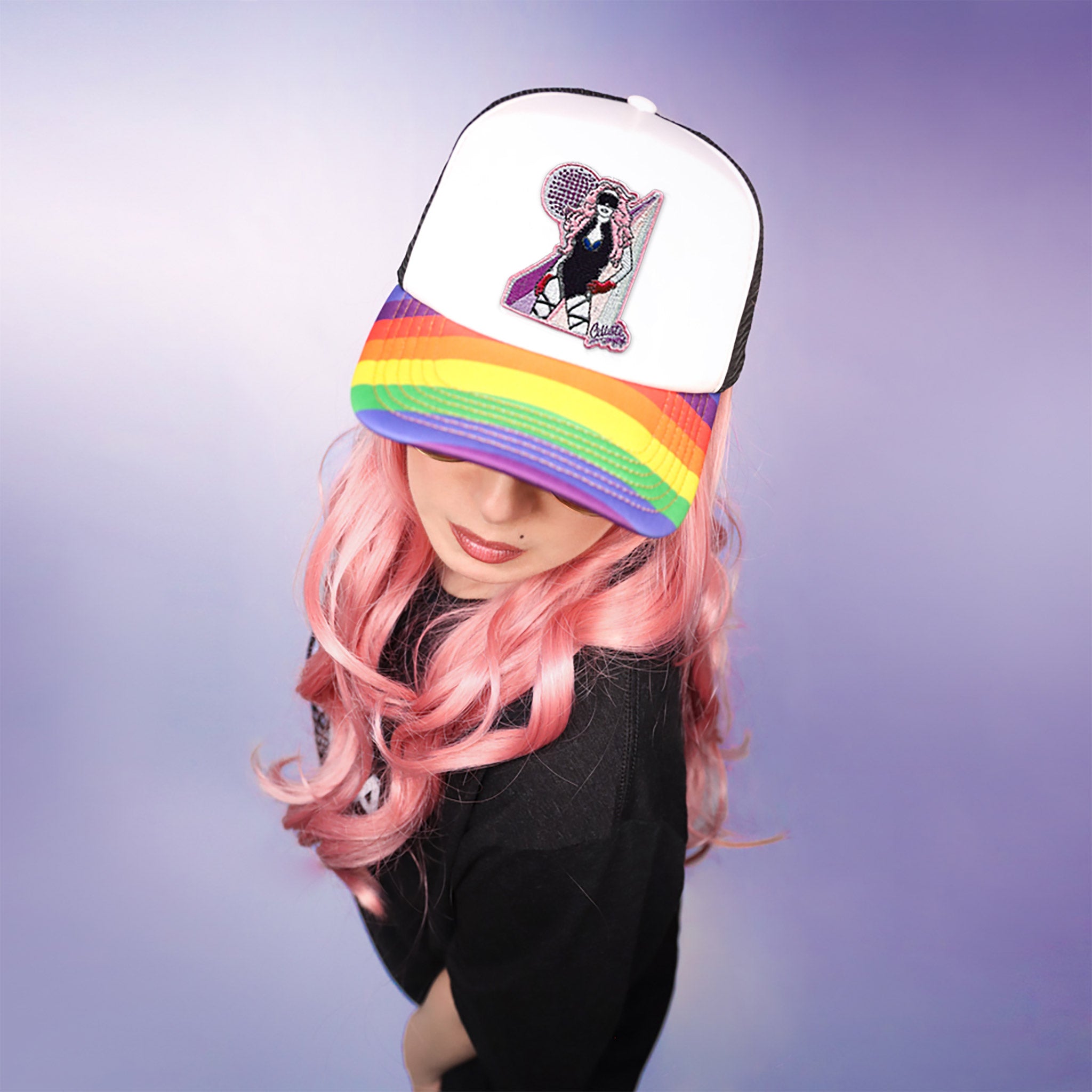 Celleste Rainbow Trucker Hat with embroidered Celleste patch. Black and white hat, rainbow beak, front view on model.